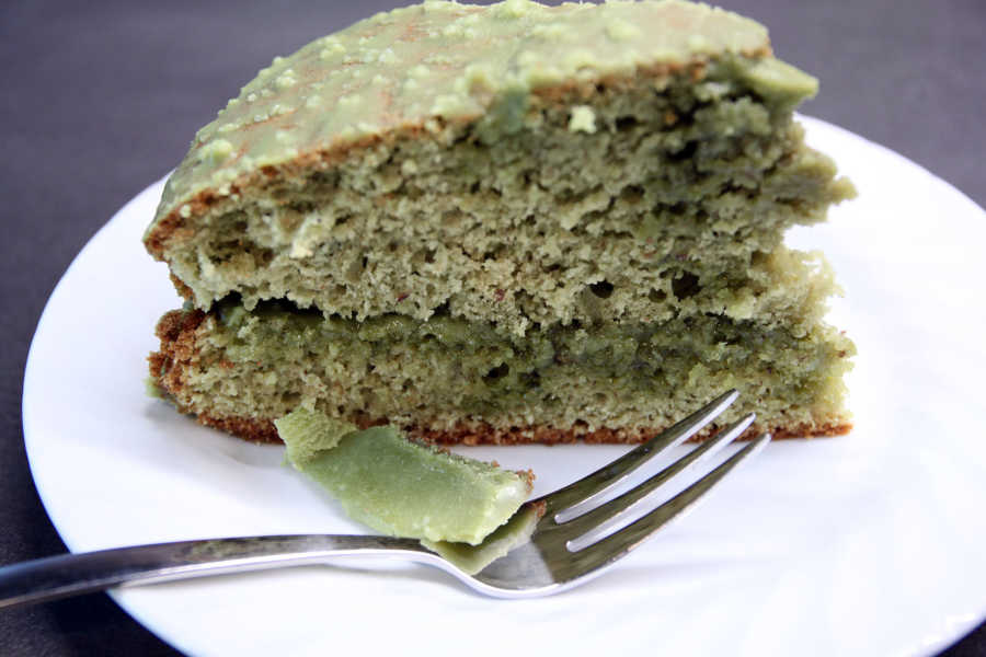Ein Stück grüner Matcha Kuchen mit weißer Schokoglasur