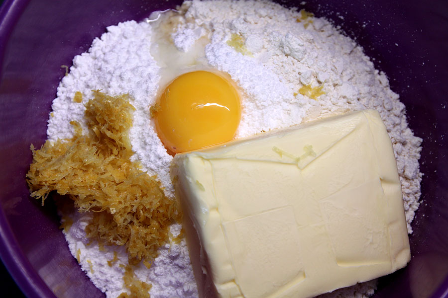 Butter, Zitronenschale, Mehl, Zucker und Ei in violetter Schüssel