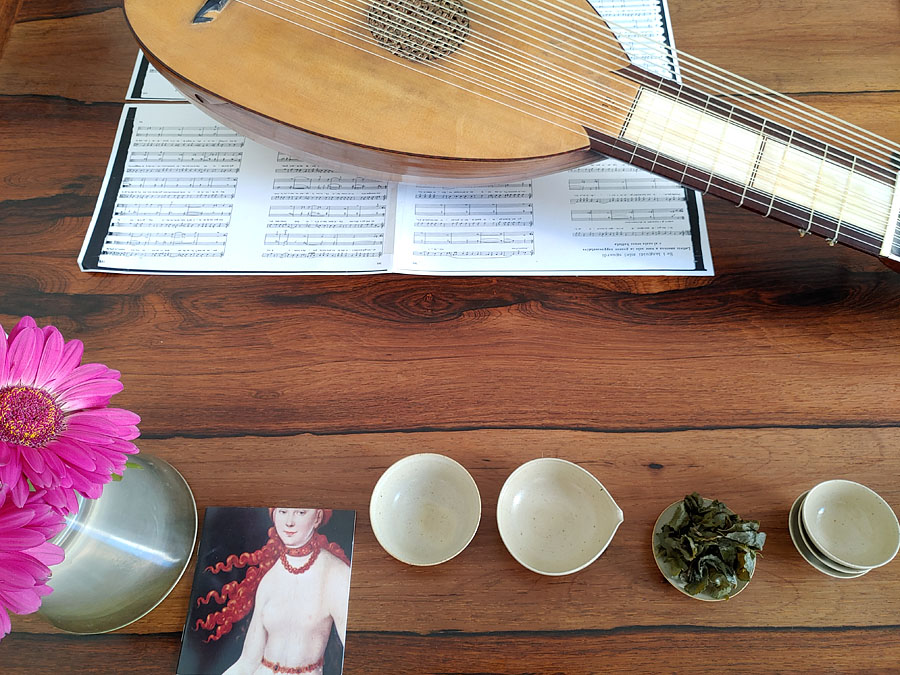Holztisch mit Blumen, Teekeramik und Musikinstrument